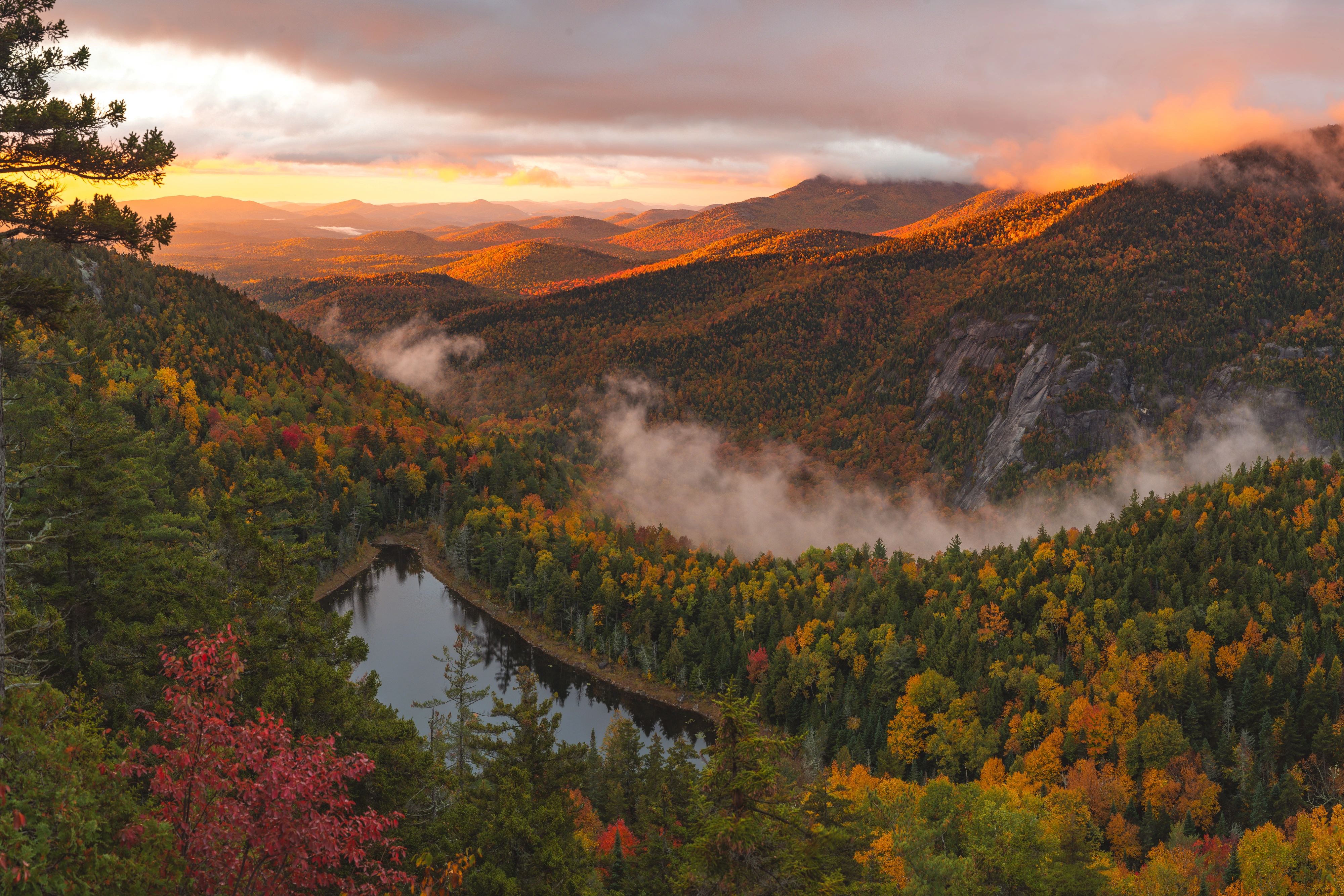 Sunrise breaks beneath a heavy ceiling of cloud while fog drifts around the Giant's Washbowl. Giant's Nubble, Giant Mountain region, Adirondacks, New York.