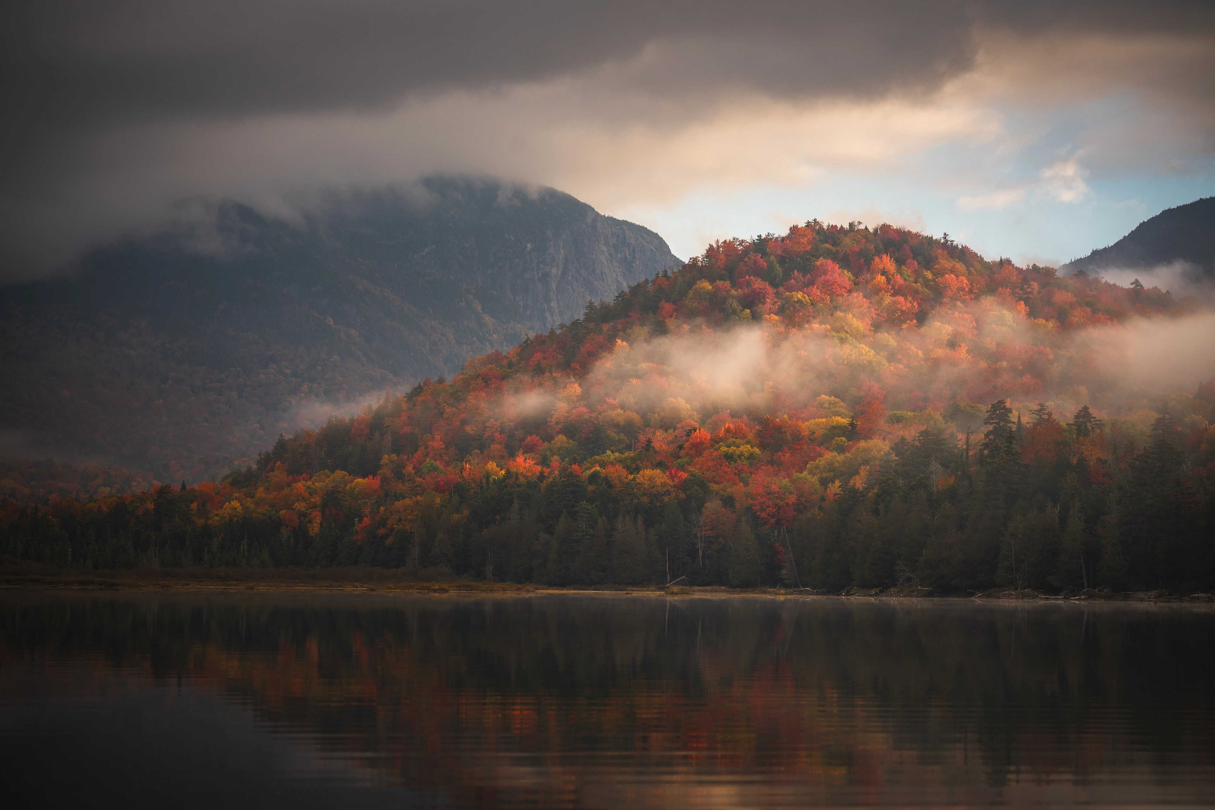 Morning light finds an autumn ridge below Wallface while fog slips through the trees. Henderson Lake, Adirondack High Peaks, New York.