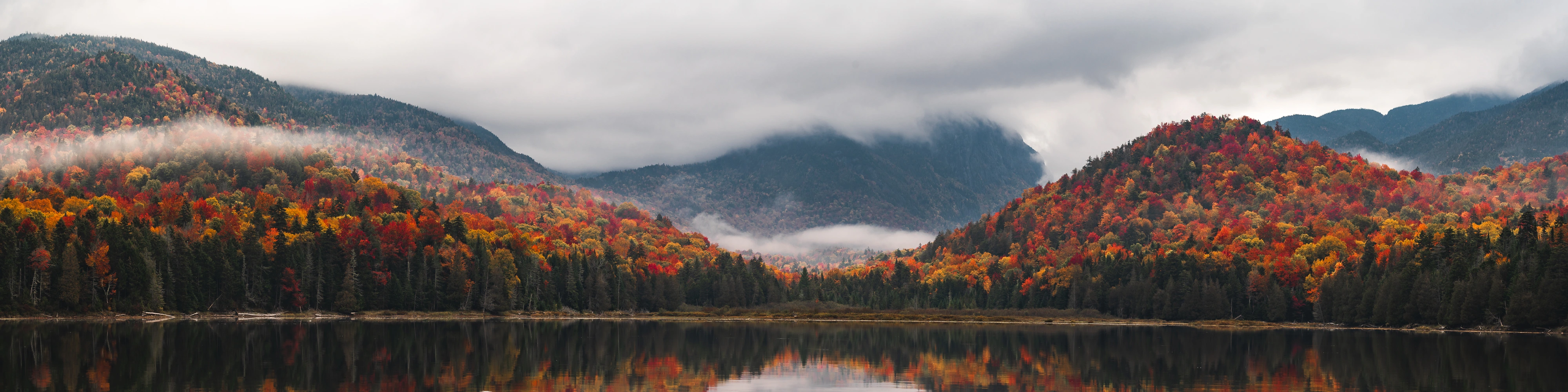 A four-to-one panorama gathers Henderson Lake, Wallface, and a low ceiling of cloud into a single quiet sweep. Henderson Lake, Adirondack High Peaks, New York.