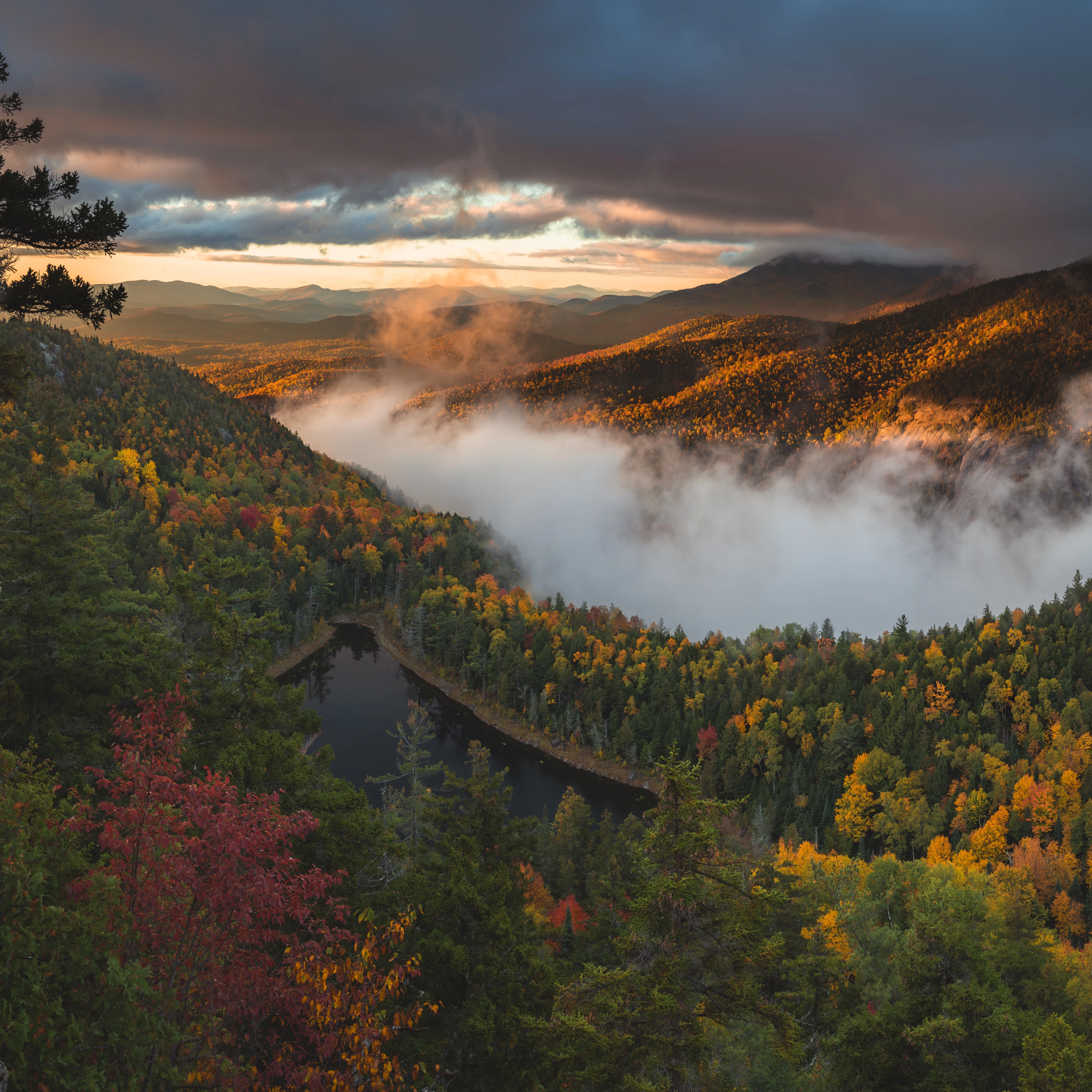 Fog spills around the Washbowl while a bright band of sunrise reaches the distant hills. Giant's Nubble, Giant Mountain region, Adirondacks, New York.