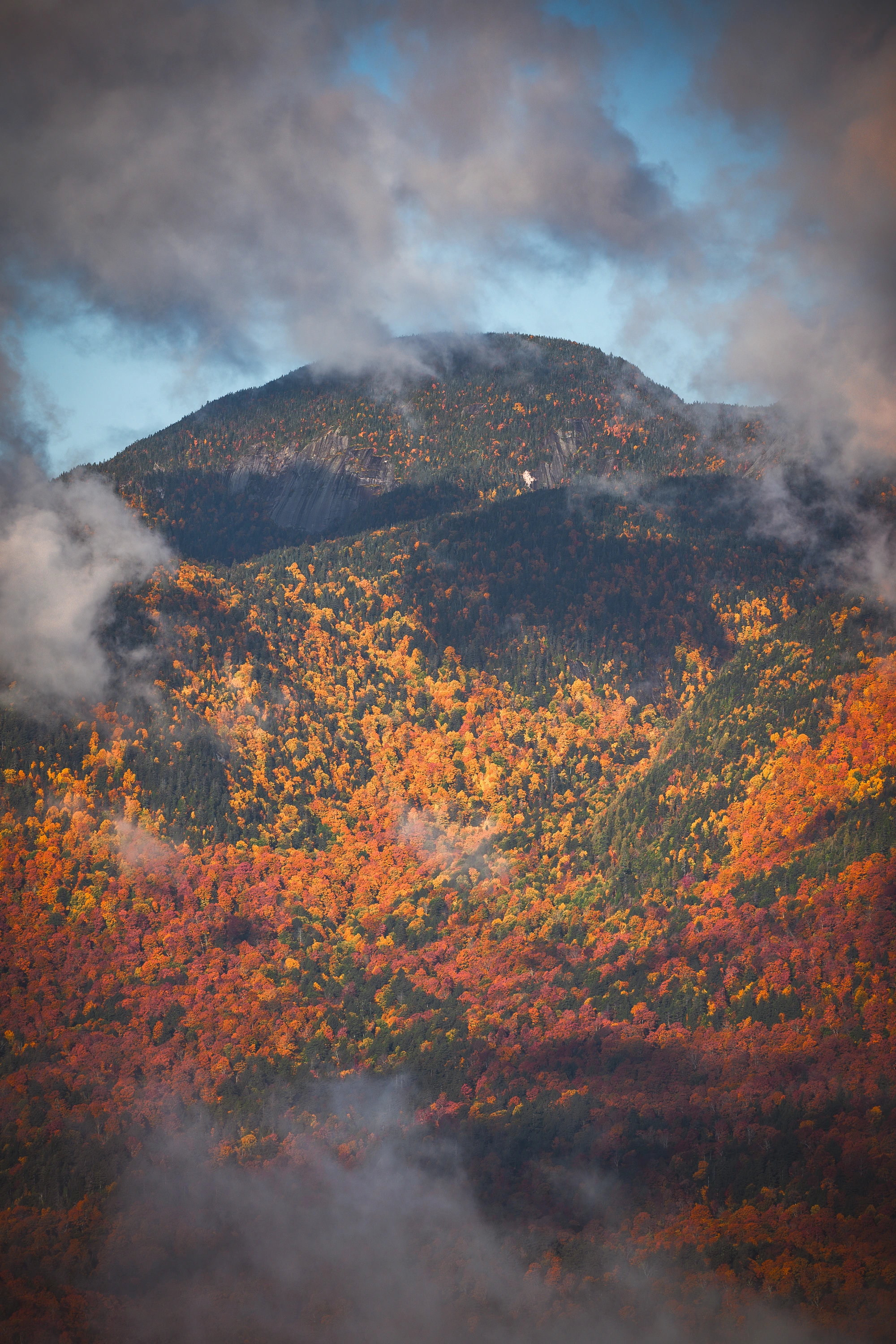 Clouds wrap Lower Wolf Jaw while reds and golds climb its forested slopes. Giant's Nubble, Giant Mountain region, Adirondacks, New York.