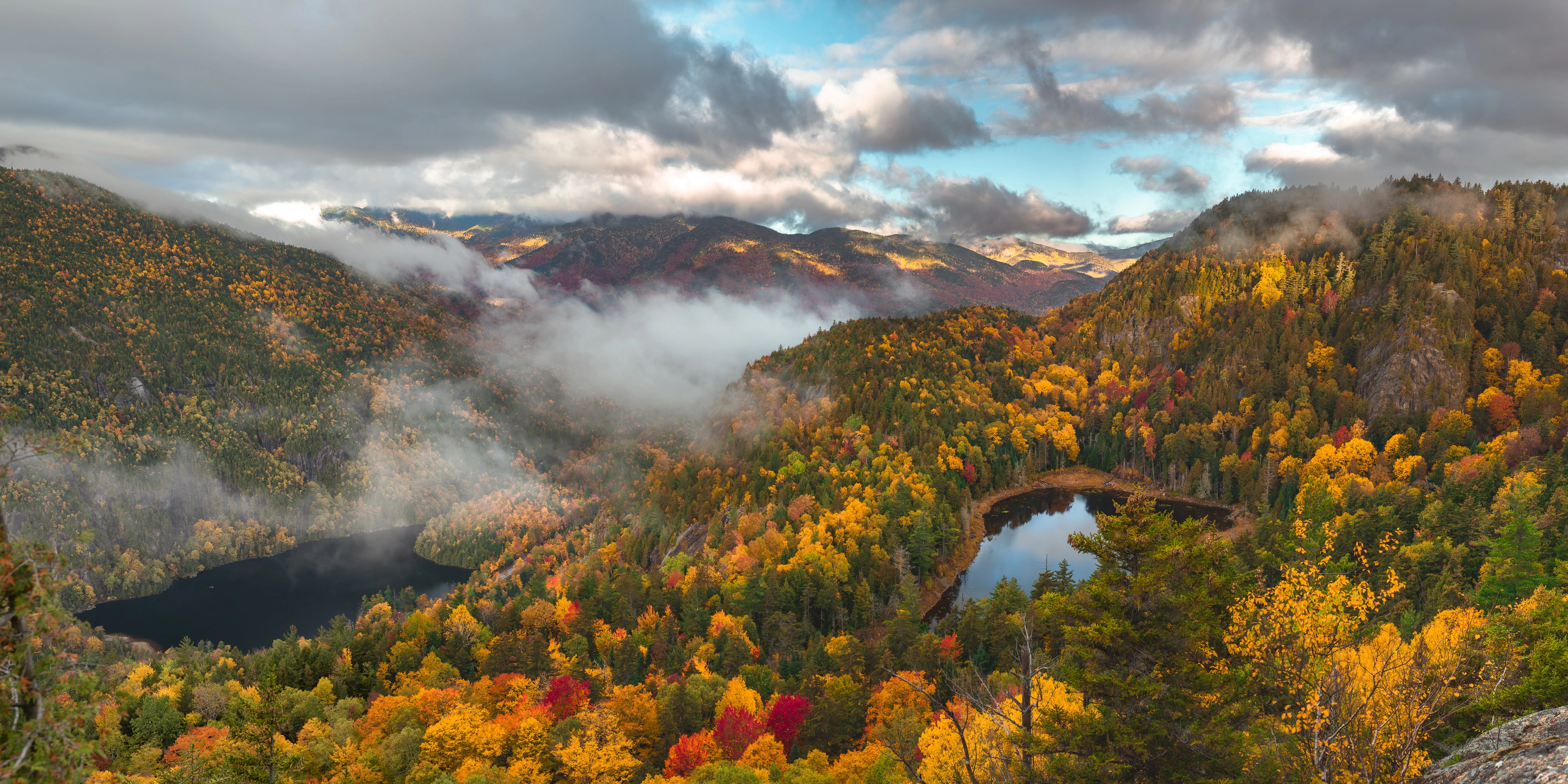 From an unnamed cliff, Chapel Pond lies to the left and Giant's Washbowl to the right, with fog moving between them. Giant Mountain region, Adirondacks, New York.