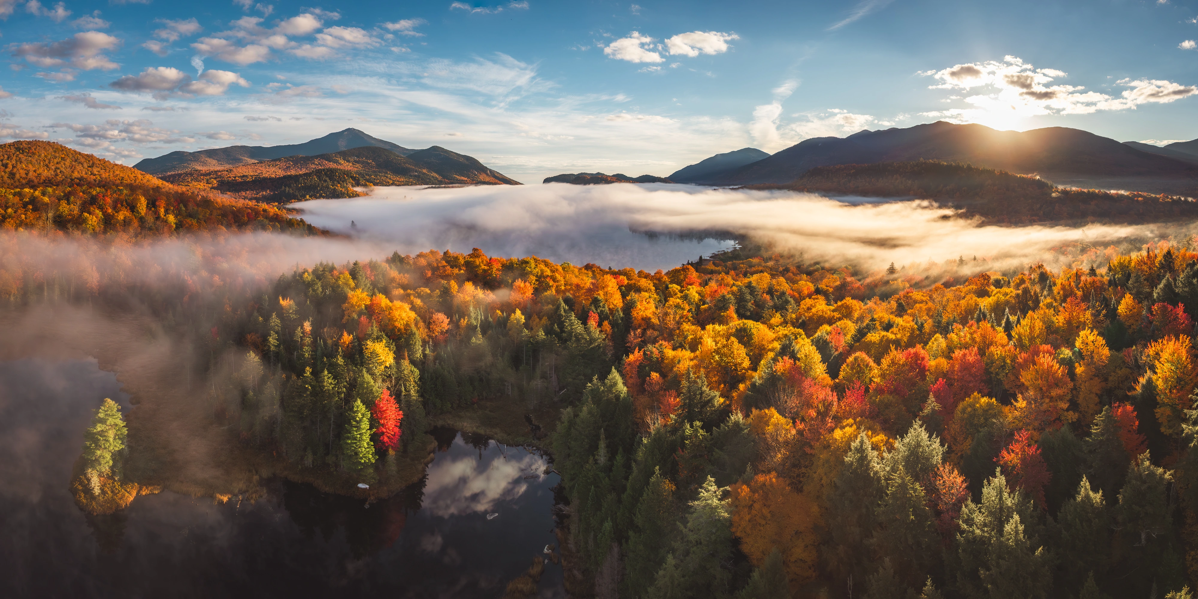 Morning sun rises over the Whiteface valley as fog pools above Connery Pond. Connery Pond, Whiteface Mountain region, Adirondacks, New York.
