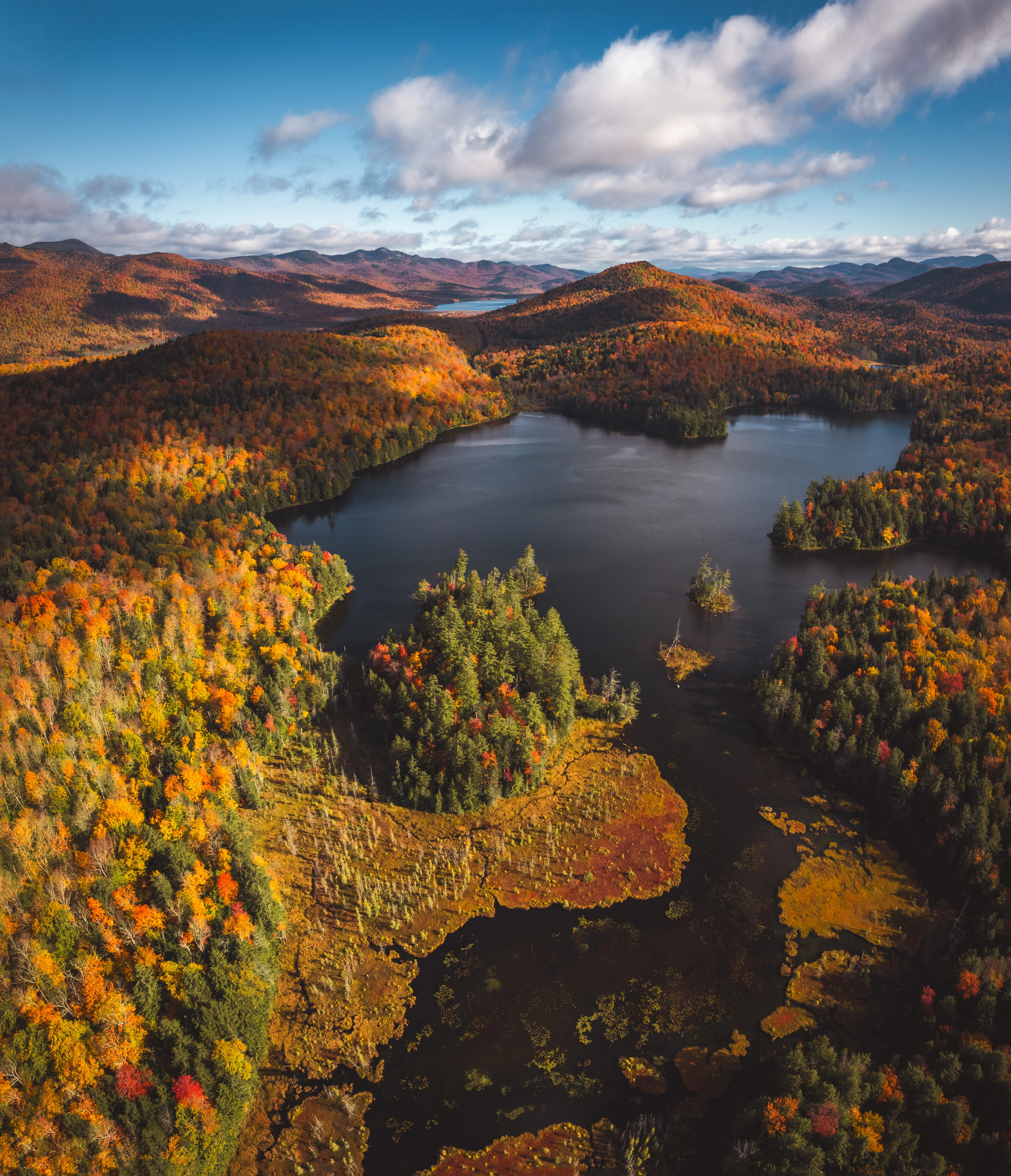 From the air above Mason Lake, bright shoreline trees trace the water into the southern Adirondack hills. Mason Lake, Hamilton County, Adirondacks, New York.